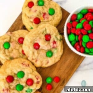 Festive M and M Christmas Cookies 11 4 homemade Christmas cookies with red and green M&Ms, sitting next to a bowl full of M&M candies.