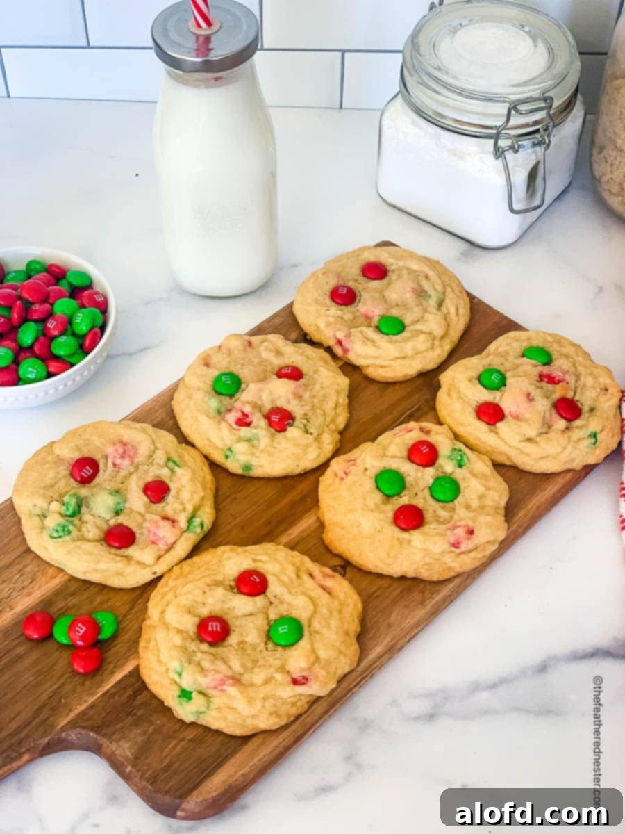 Festive M and M Christmas Cookies 3 a wooden board with Christmas M and M cookies with a glass of milk at the side.
