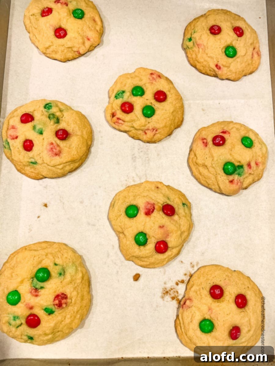Festive M and M Christmas Cookies 7 Parchment paper lined baking sheet with baked Christmas M&M cookies.