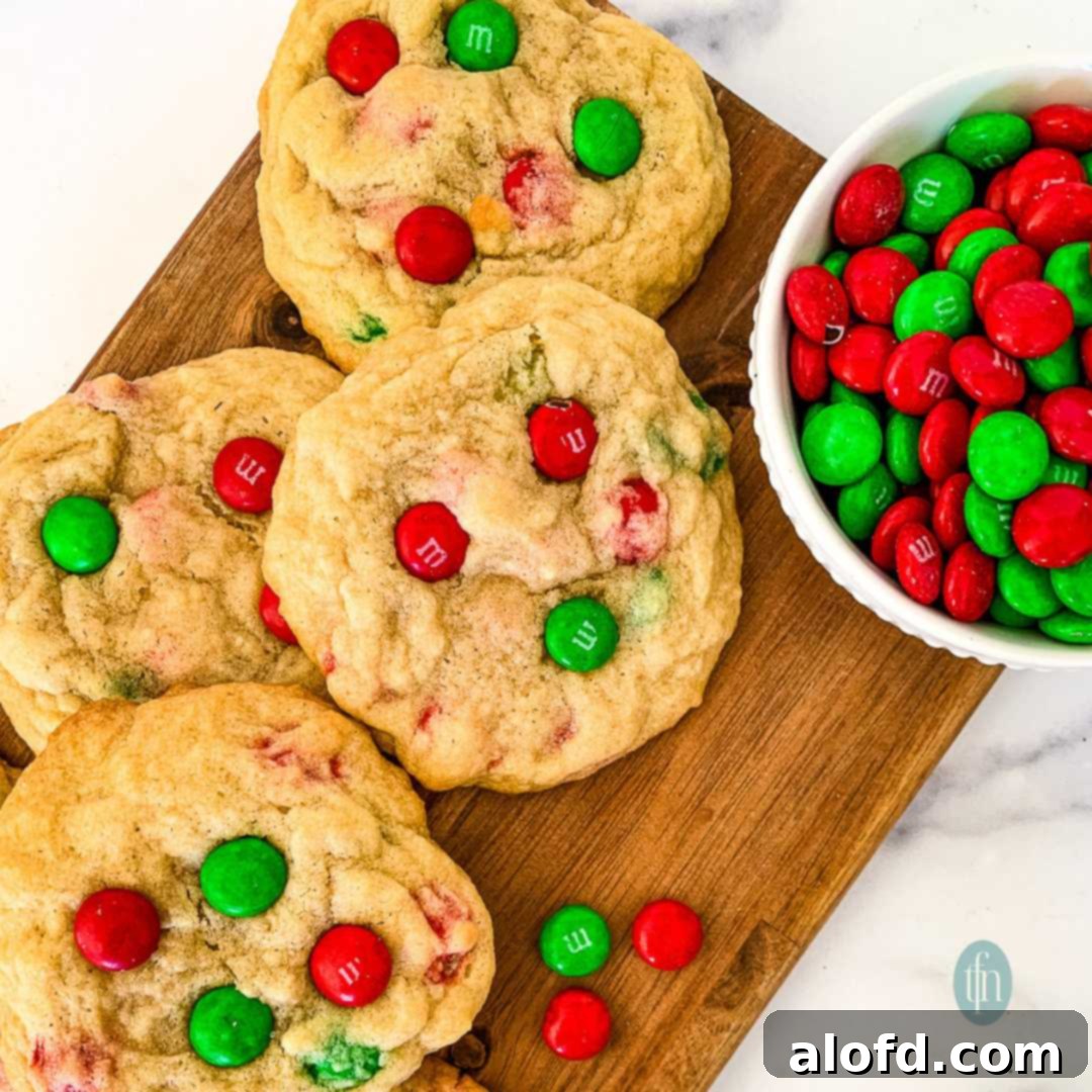 Festive M and M Christmas Cookies 10 4 homemade Christmas cookies with red and green M&Ms, sitting next to a bowl full of M&M candies.