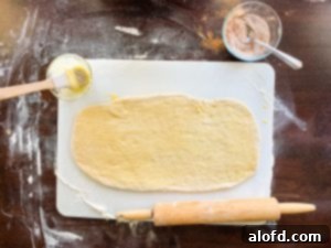 Applying melted butter to the rolled-out dough, prepared for the pumpkin spice filling.