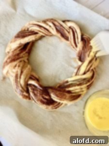 Brushing the pumpkin spice bread twist with an egg wash before baking.