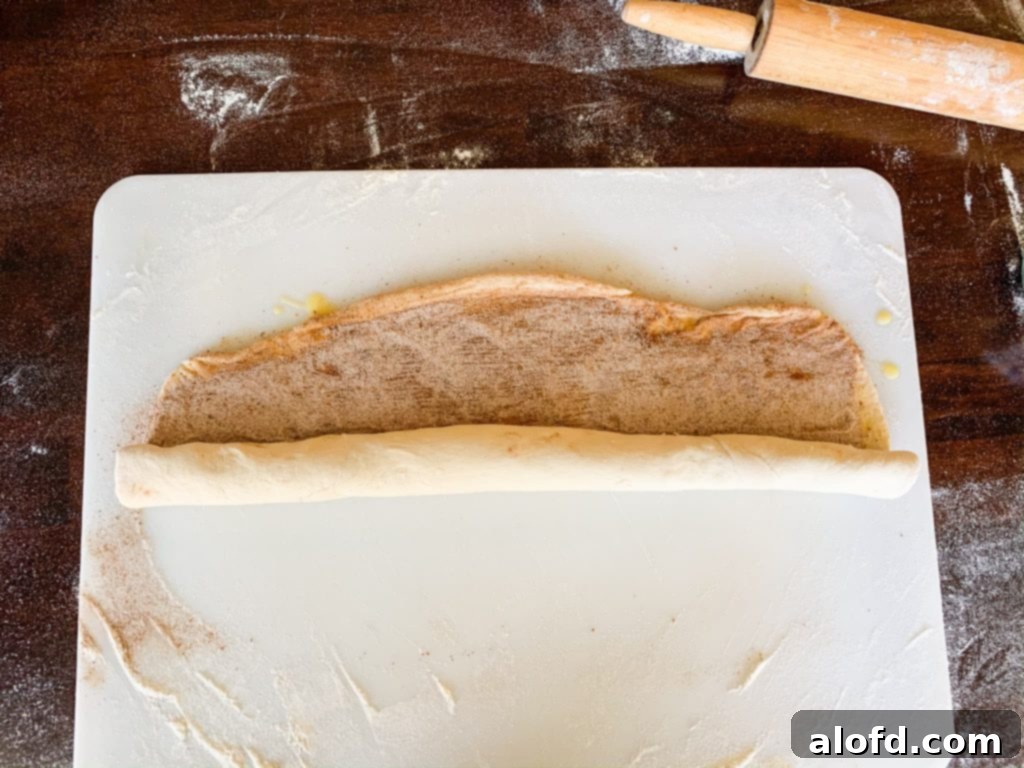 Carefully rolling up the pumpkin spice bread dough log, jelly-roll style.