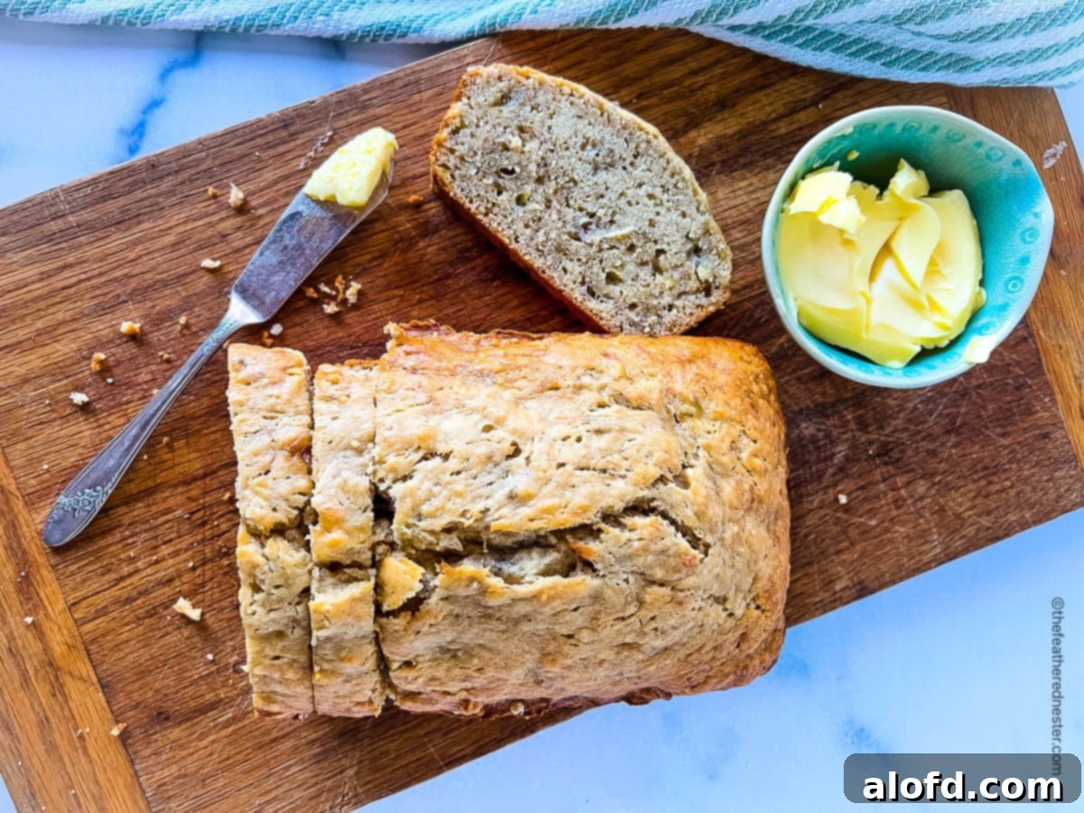 A beautifully sliced loaf of Bisquick banana bread on a wooden cutting board, with butter and a bread knife.