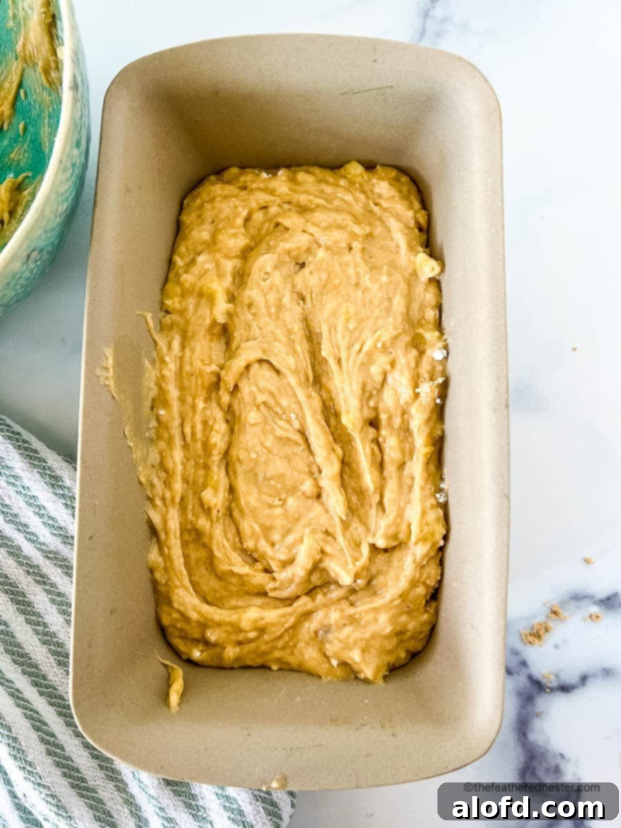 Smooth Bisquick banana bread batter poured into a greased loaf pan, ready for baking.