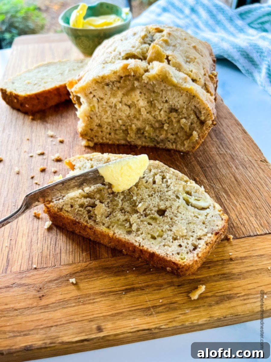 A hand spreading butter on a slice of warm, moist Bisquick banana bread.