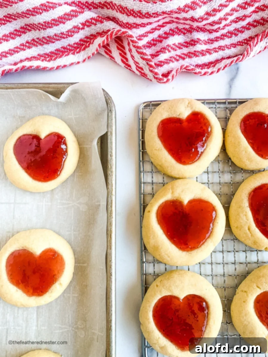 Two baking sheets with Valentine cookies, with some on a cooling rack.