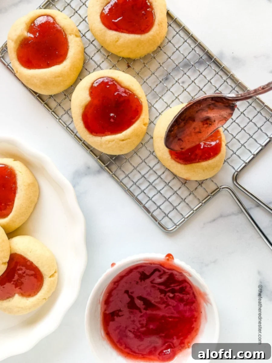 Filling heart jam cookies with red preserves.