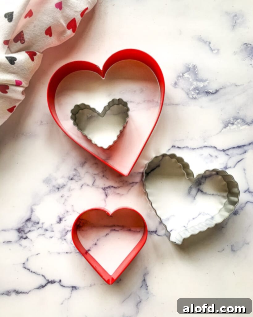 A delightful collection of heart-shaped cookie cutters in various sizes, neatly arranged on a pristine marble countertop, ready to create charming Valentine's Day treats.