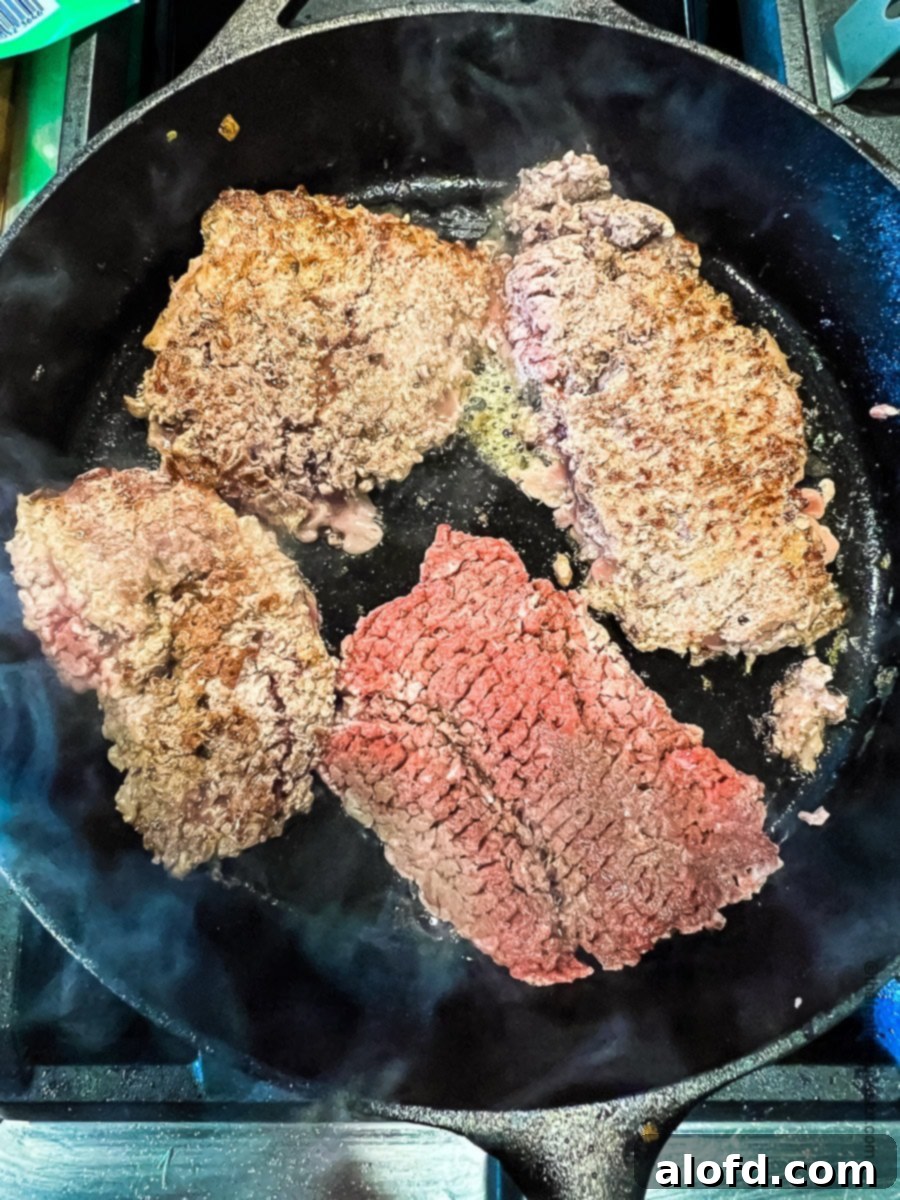 Tender Slow Cooker Swiss Steak 5 Browning cube steaks in a skillet.