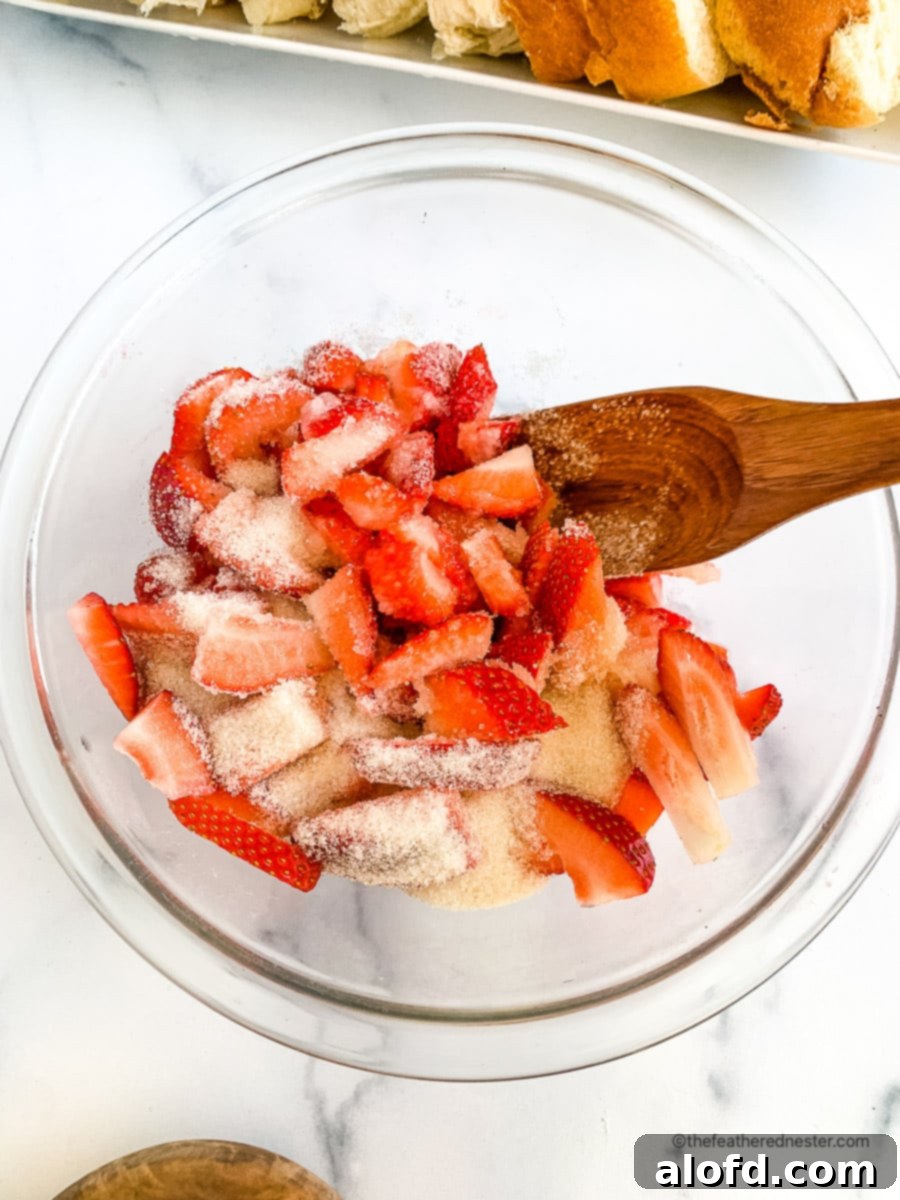 Luscious Strawberry French Toast 4 Wooden spoon in a bowl of macerated strawberries, ready for syrup preparation.