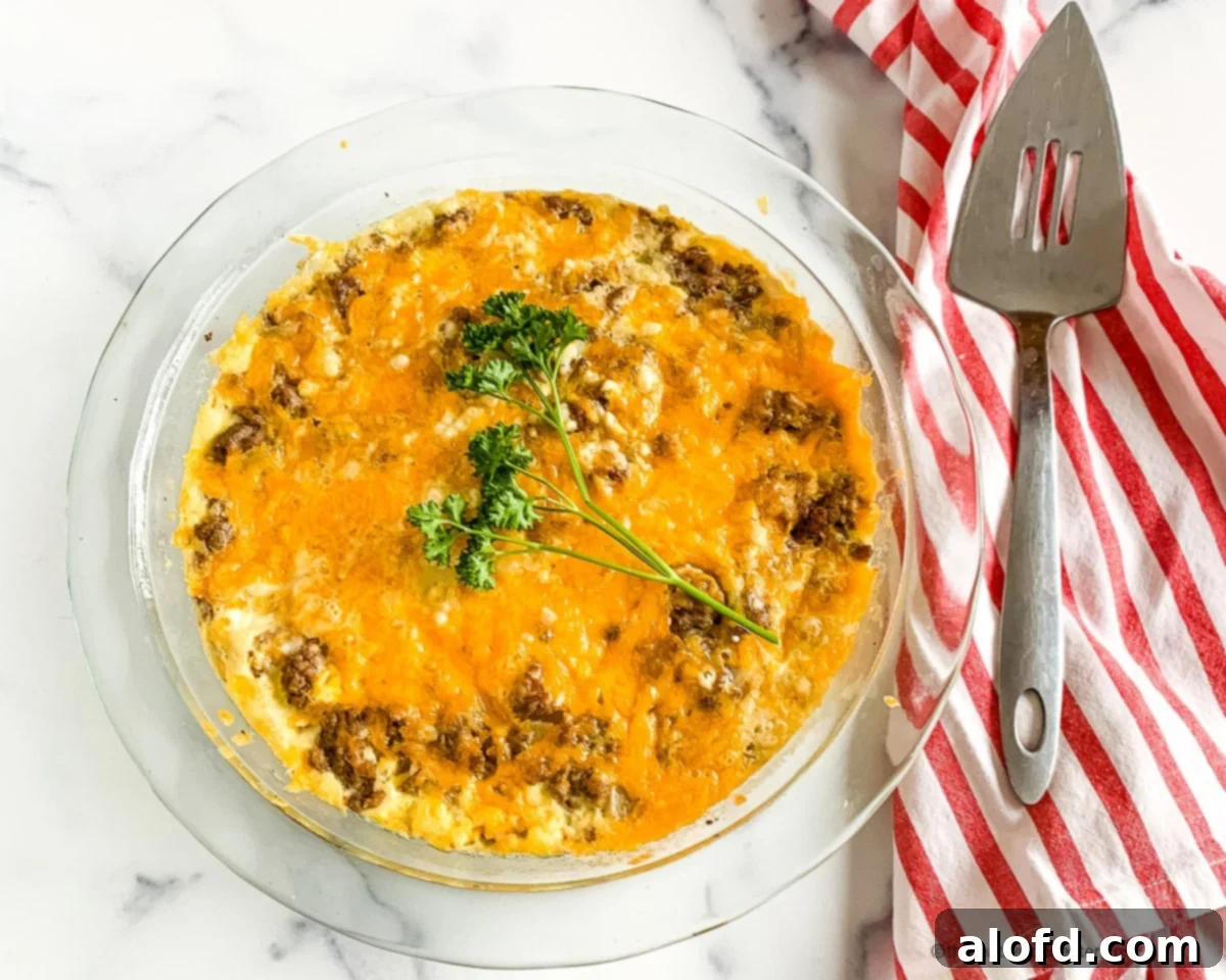 Hearty Bisquick Cheeseburger Bake 3 Pie server on red and white striped napkin next to an unsliced Bisquick impossible pie in a glass pie plate.