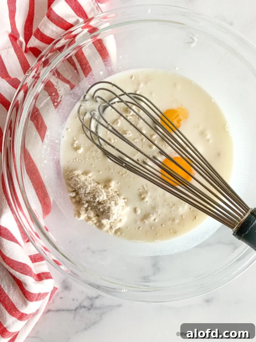 Hearty Bisquick Cheeseburger Bake 5 Using a whisk to combine eggs with milk and baking mix in a glass mixing bowl.