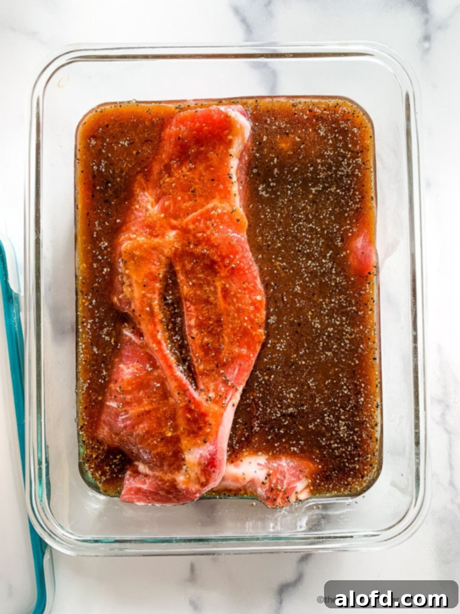 Raw pork chops marinating in a glass bowl, absorbing the flavors.