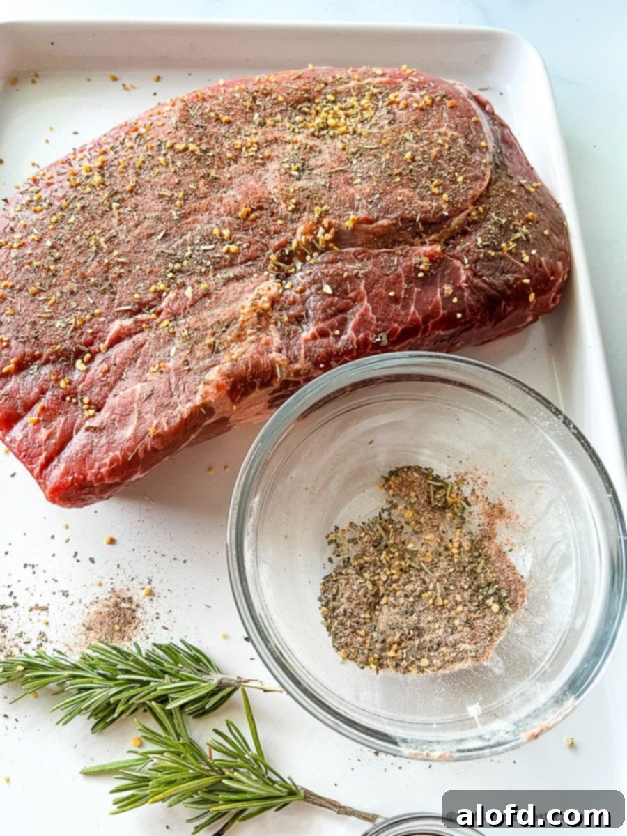 Fall-Apart Slow Cooker Sirloin Tip Roast 5 Three pounds of seasoned boneless sirloin roast next to small bowl of dried seasoning.