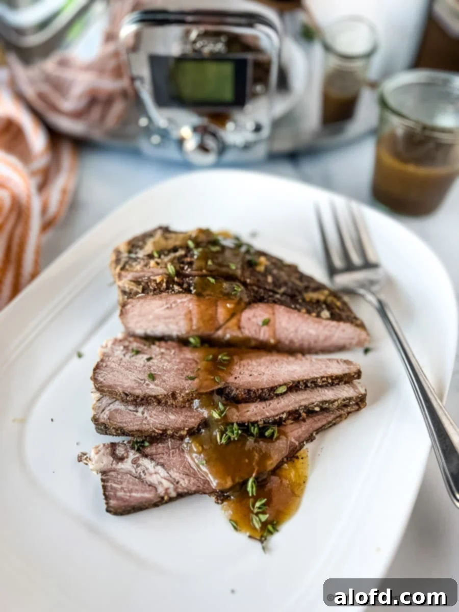 Fall-Apart Slow Cooker Sirloin Tip Roast 6 Sunday dinner of sliced beef and gravy on a white serving platter.