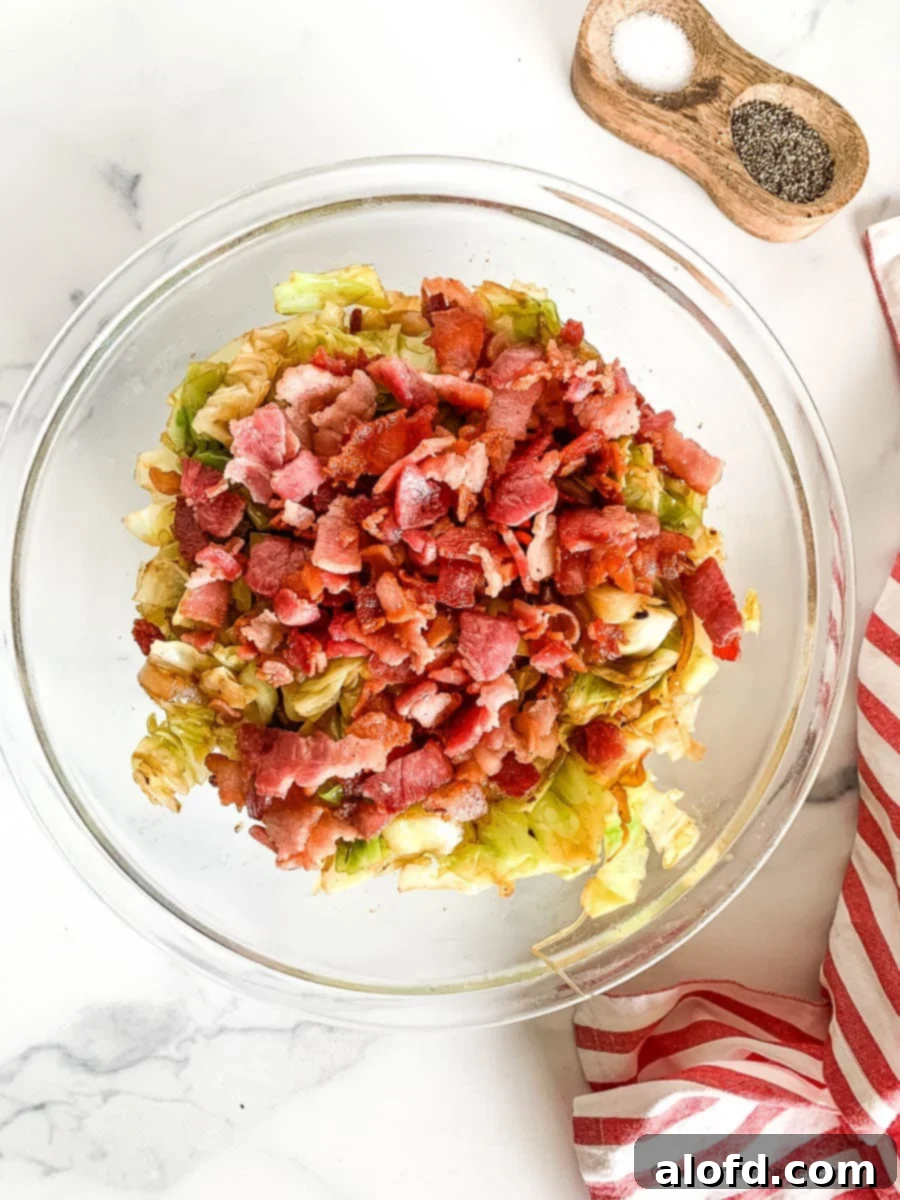 Fried cabbage with bacon in a large glass serving bowl.