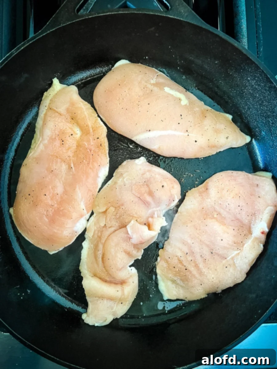 Perfectly Seared Cast Iron Chicken Breast 6 Four raw boneless skinless chicken breasts in a black skillet.