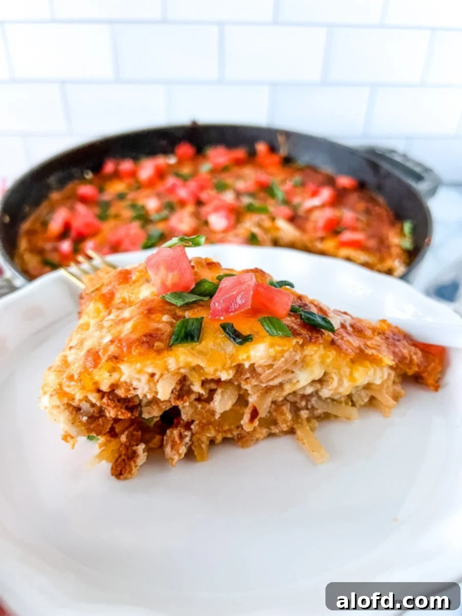 Serving of Bisquick breakfast casserole on a white plate, with remaining egg casserole in the background.