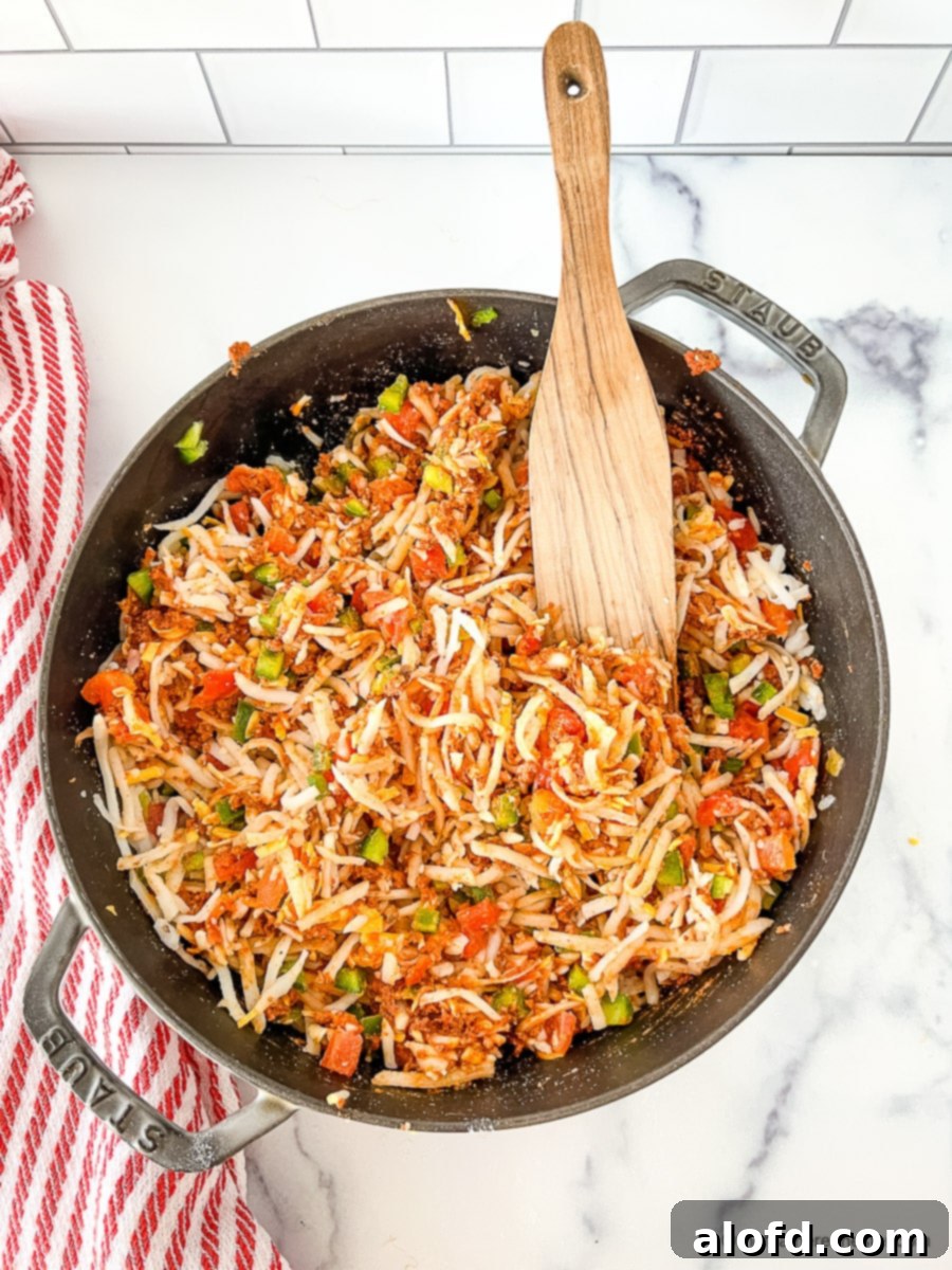 Wooden spoon in pot with shredded hash browns, diced vegetables and other ingredients for Tex Mex egg bake.
