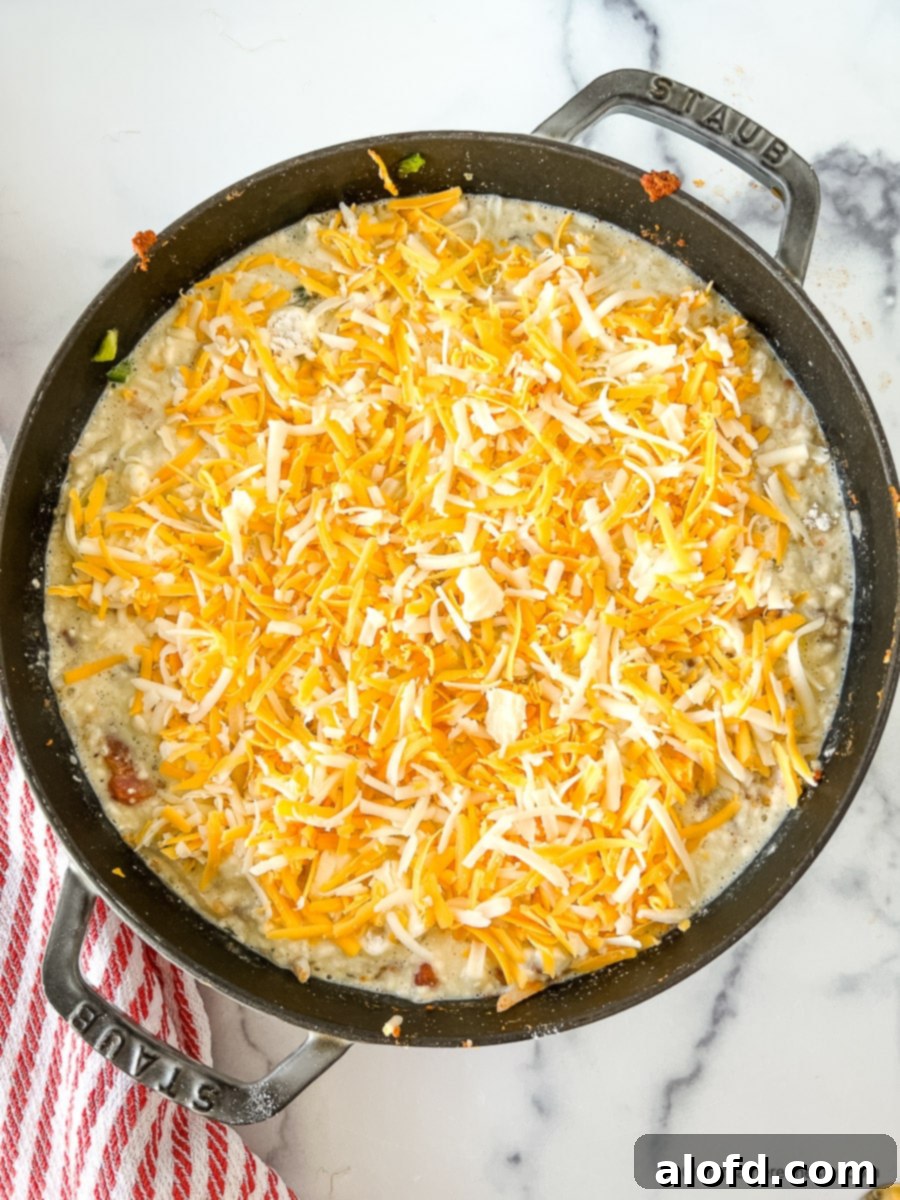 Shredded cheese on top of an uncooked breakfast bake.