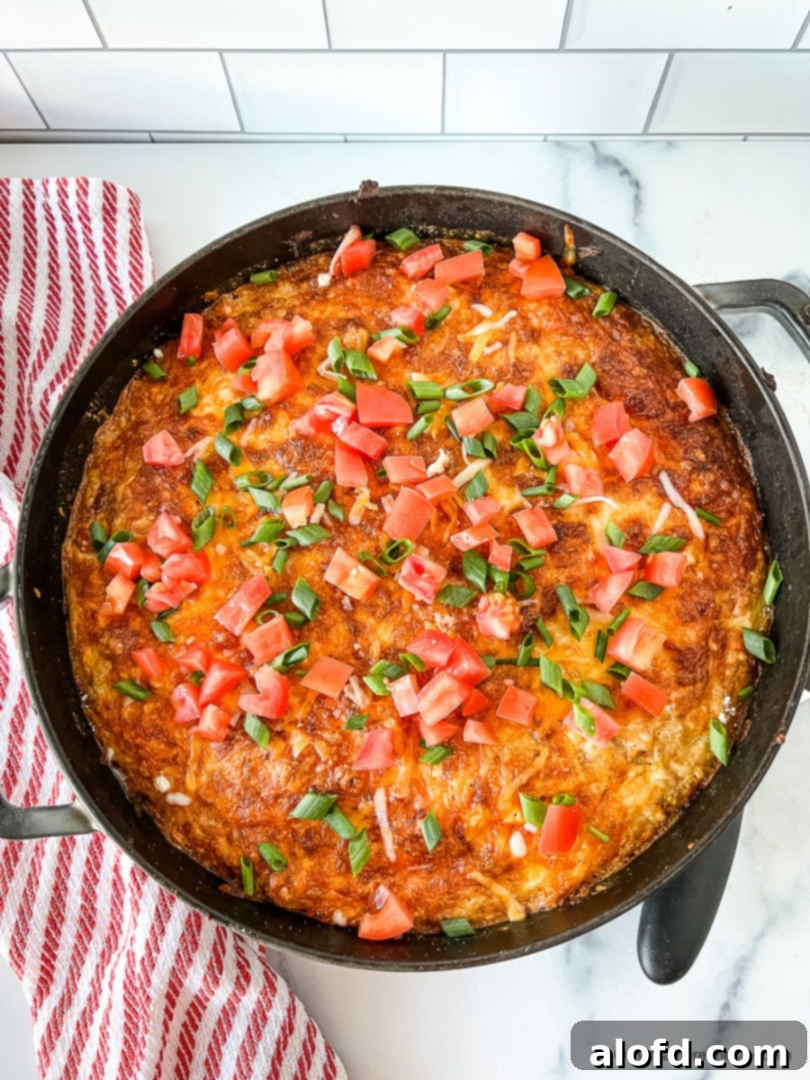 Tex Mex casserole topped with diced tomatoes and scallions.
