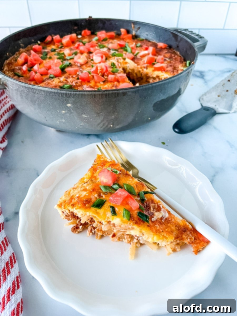 Slice of baked eggs with chorizo on a white plate with a fork. Round cast iron pot in the background.