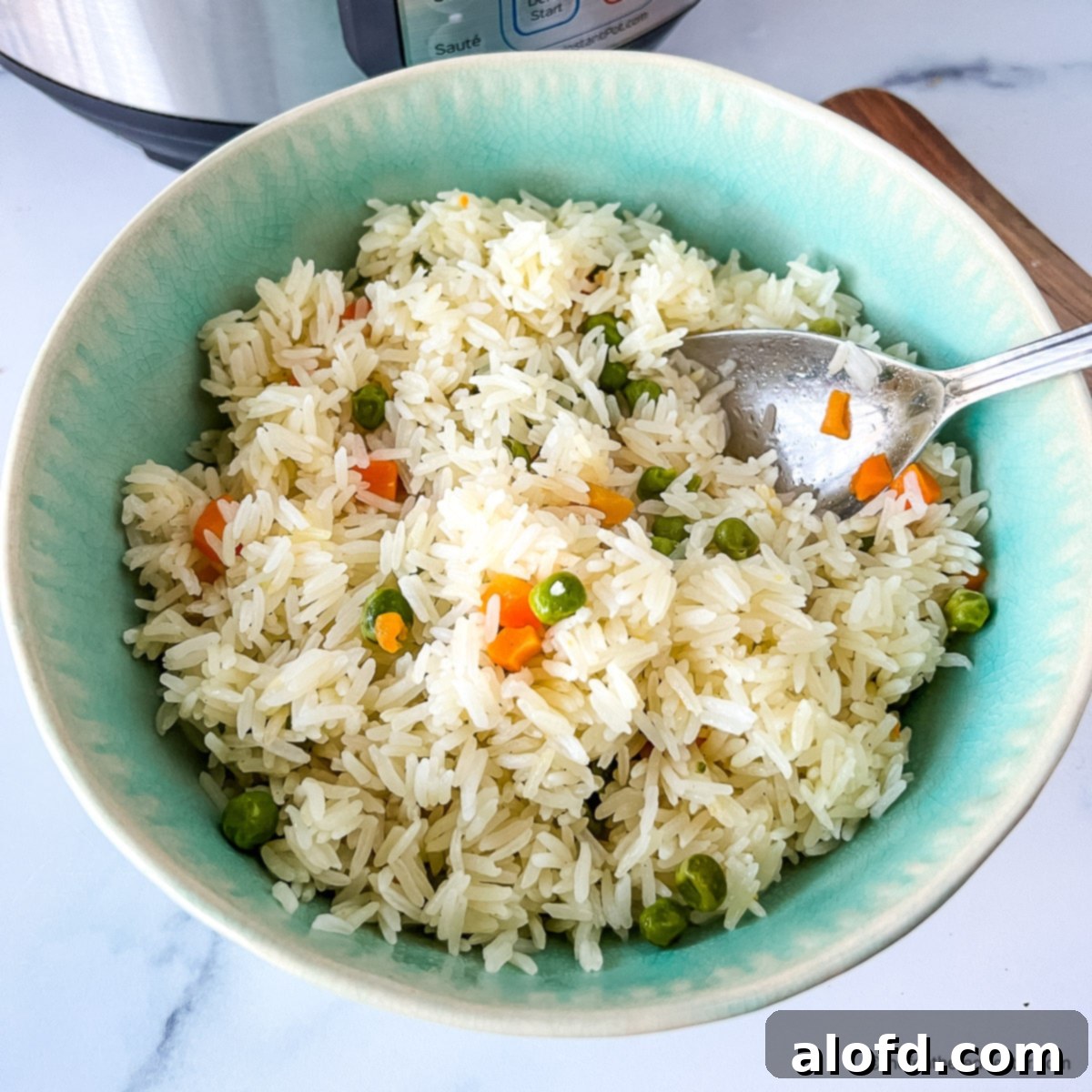 A vibrant green serving bowl filled with steaming Instant Pot rice pilaf, topped with fresh herbs and a serving spoon, highlighting its fluffy texture.