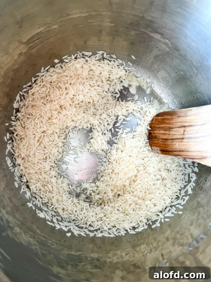 Close-up of Basmati rice grains being sautéed in an Instant Pot with butter, turning slightly golden.