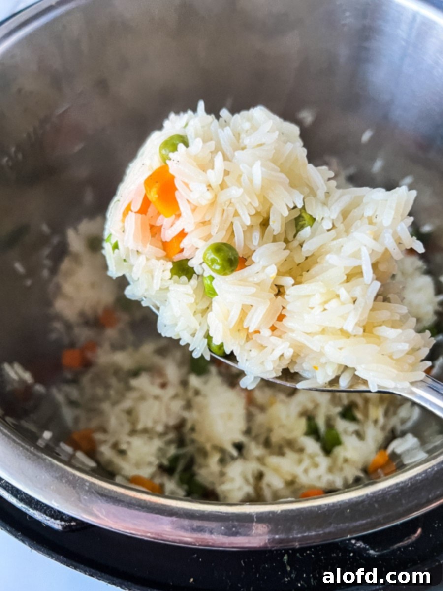 A large serving spoon scooping vegetable rice pilaf from a pressure cooker, showcasing its light and fluffy texture.