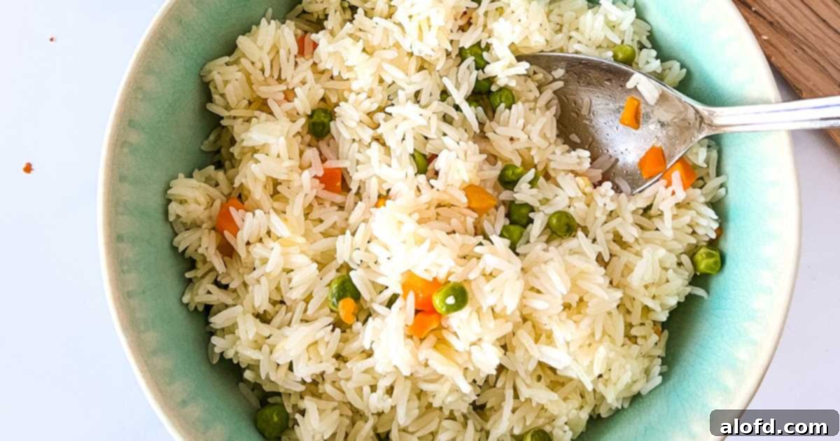 A close-up shot of a spoon in a bowl of fluffy Instant Pot vegetable rice pilaf, showcasing its texture and colorful ingredients.