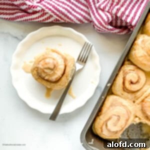 Fluffy Sourdough Discard Cinnamon Rolls 15 A fork and cinnamon bun on a round white plate, showing the soft interior.