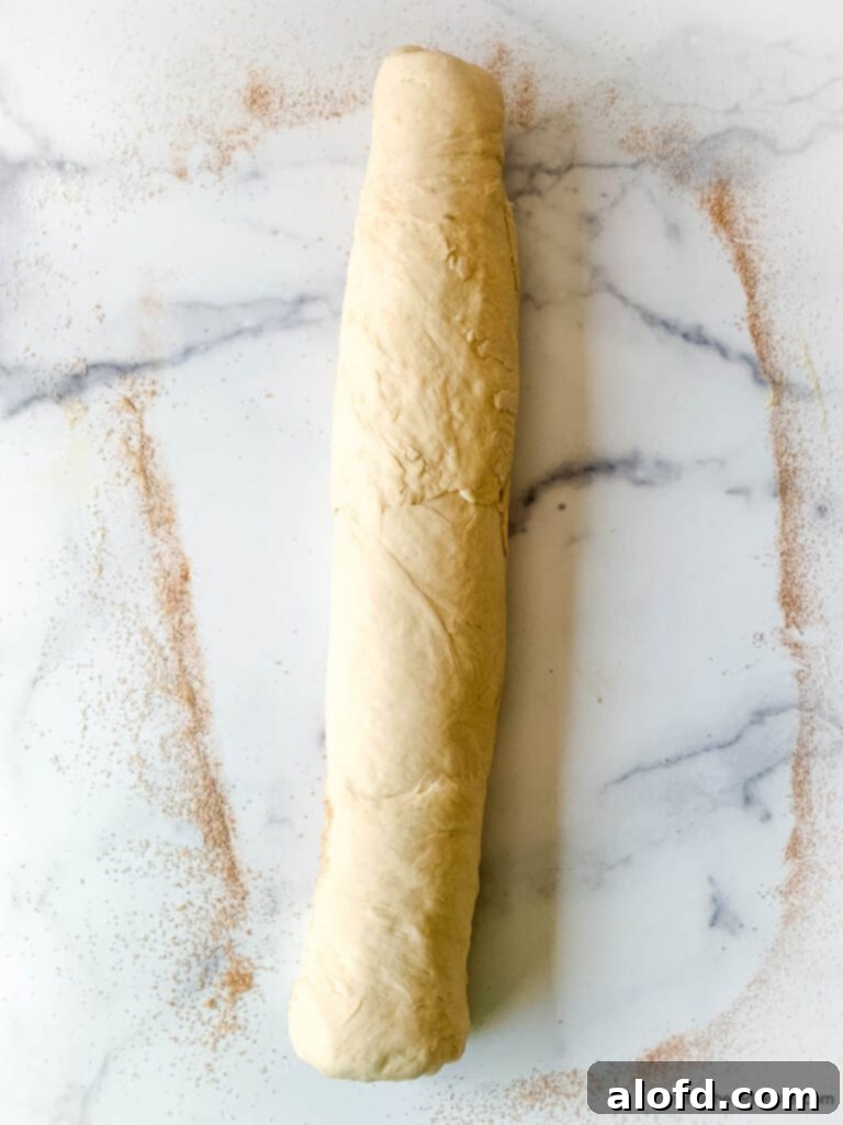 Fluffy Sourdough Discard Cinnamon Rolls 10 A large piece of sweet yeast dough, perfectly rolled and ready for slicing, on a clean marble countertop.