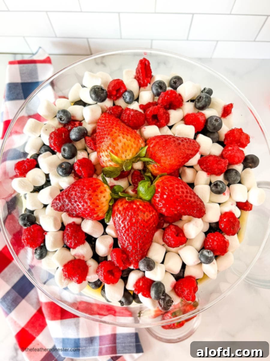 An inviting overhead shot looking down into a beautifully arranged bowl of Red, White, and Blue Cheesecake Salad, showcasing its patriotic colors and creamy texture.