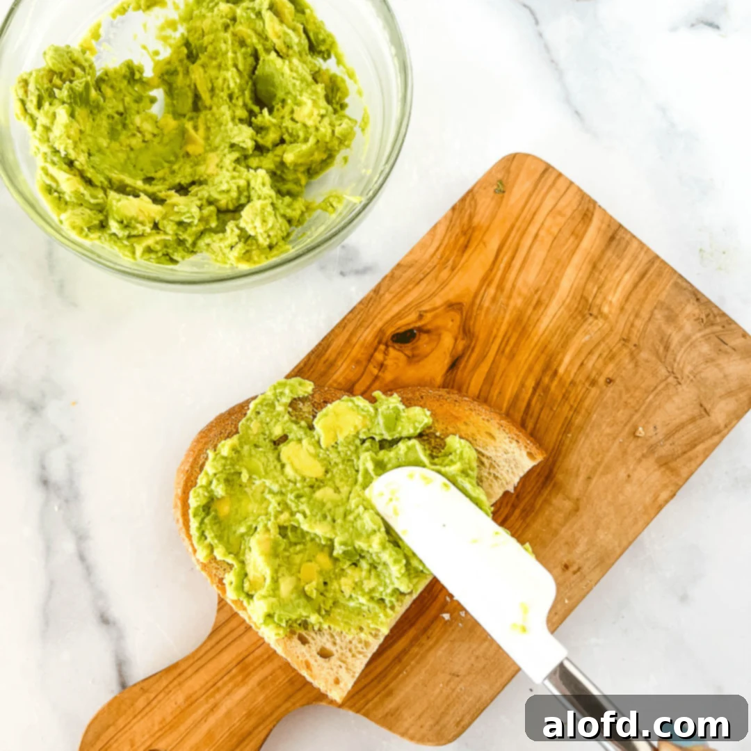 Velvet Avocado Spread 11 Using a spatula to spread creamy avocado on a slice of toast.