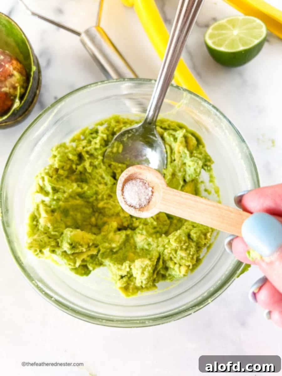 Velvet Avocado Spread 8 Adding a teaspoon of salt to a bowl with creamy avocado spread.