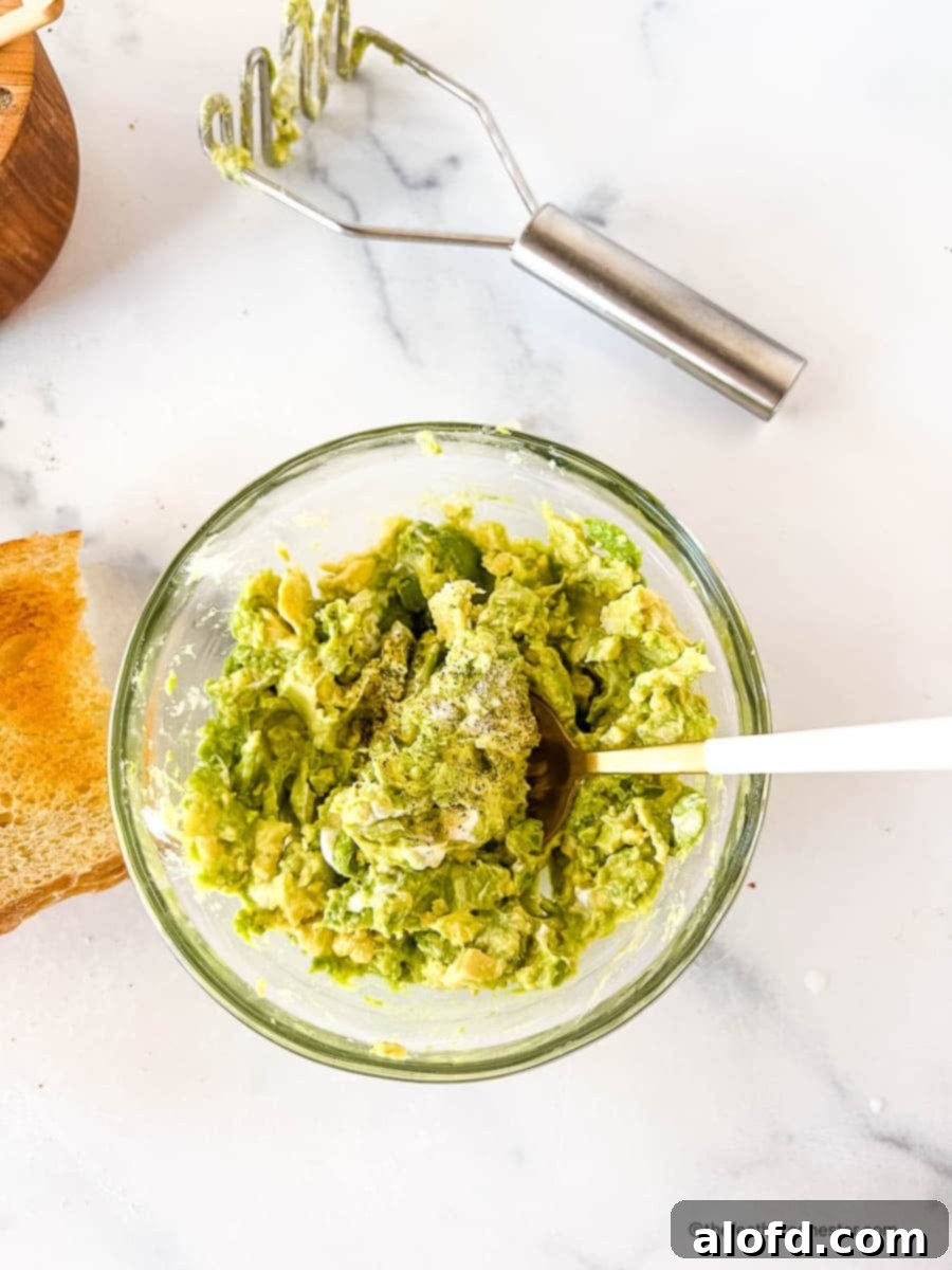 Velvet Avocado Spread 9 Bowl of mashed avocados with seasonings and a spoon.