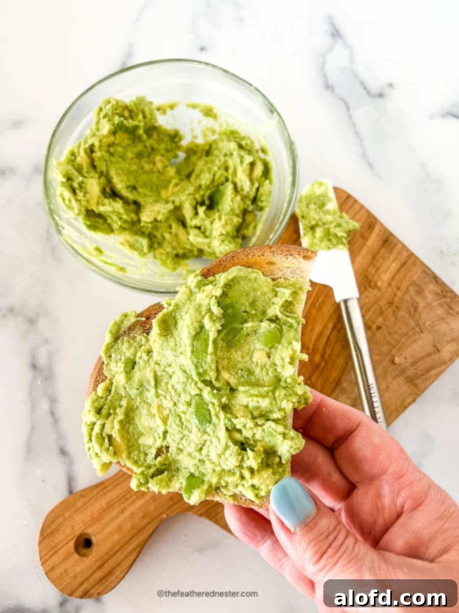 Velvet Avocado Spread 10 Bowl of green topping for toast in a small glass bowl and spread on a slice of bread.