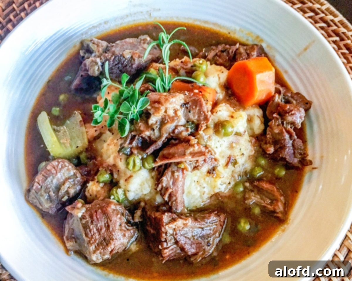 Speedy Savory Beef Stew 5 A bowl of Instant Pot Beef Stew served over a bed of mashed potatoes, garnished with fresh herbs, ready for a hearty meal.