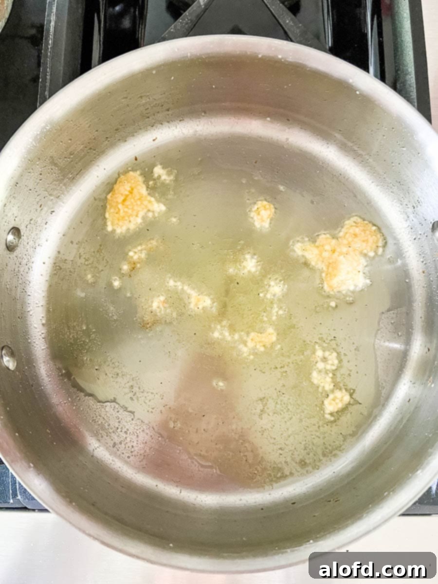 Sautéing garlic in a skillet with olive oil as the first step in making pomodoro sauce.
