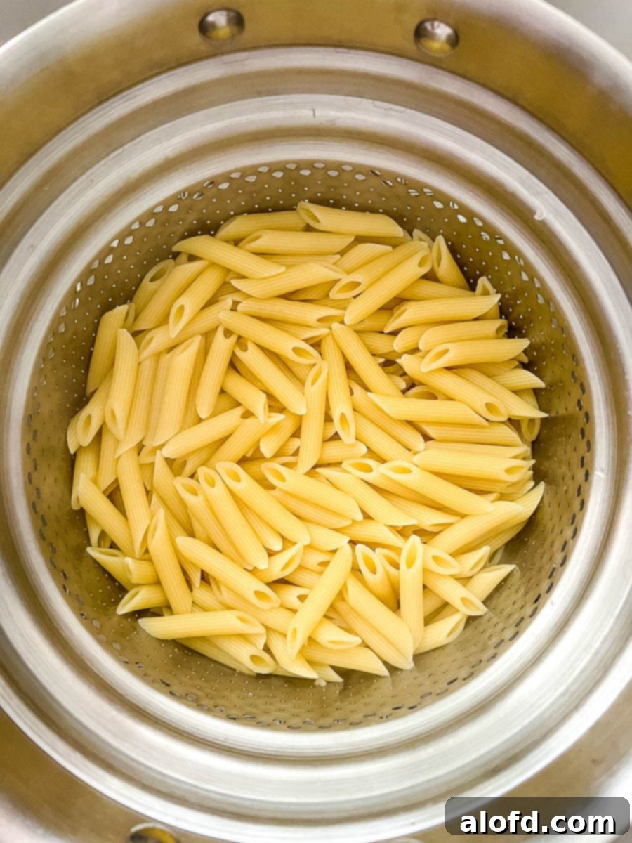 Al dente penne pasta in a colander, freshly drained.
