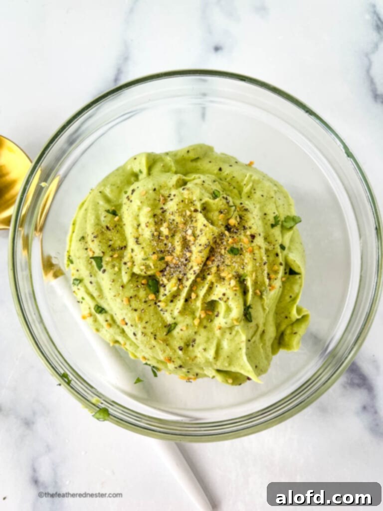 Avocado crema party food in a round glass dish, garnished with fresh cilantro, ready to be served as a delightful dip or topping.