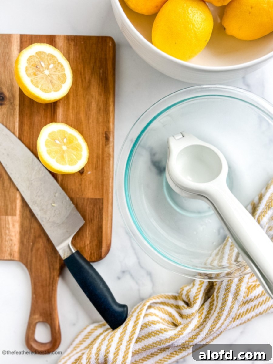 chef's knife on a cutting board next to a large glass bowl with a citrus press.