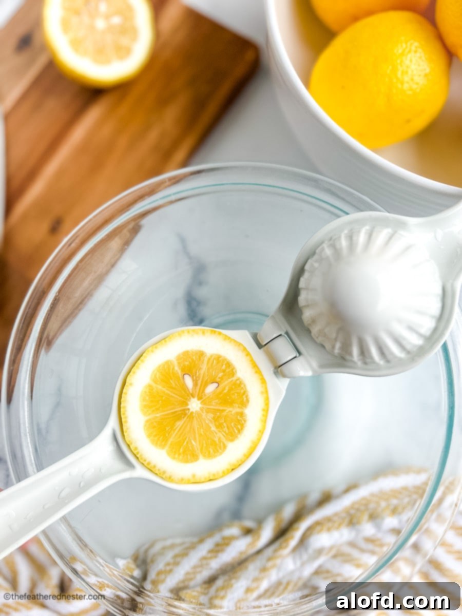Squeezing fresh lemons in a glass bowl for homemade lemonade.