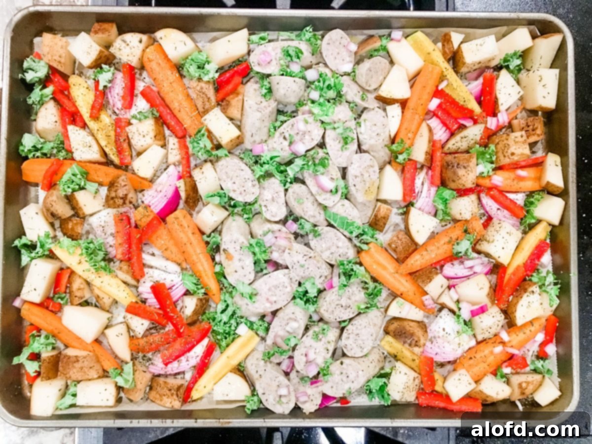 One-Pan Chicken Sausage and Roasted Vegetables 5 A sheet pan loaded with pre-cooked chicken sausage and various chopped vegetables, perfectly seasoned and ready for the oven.