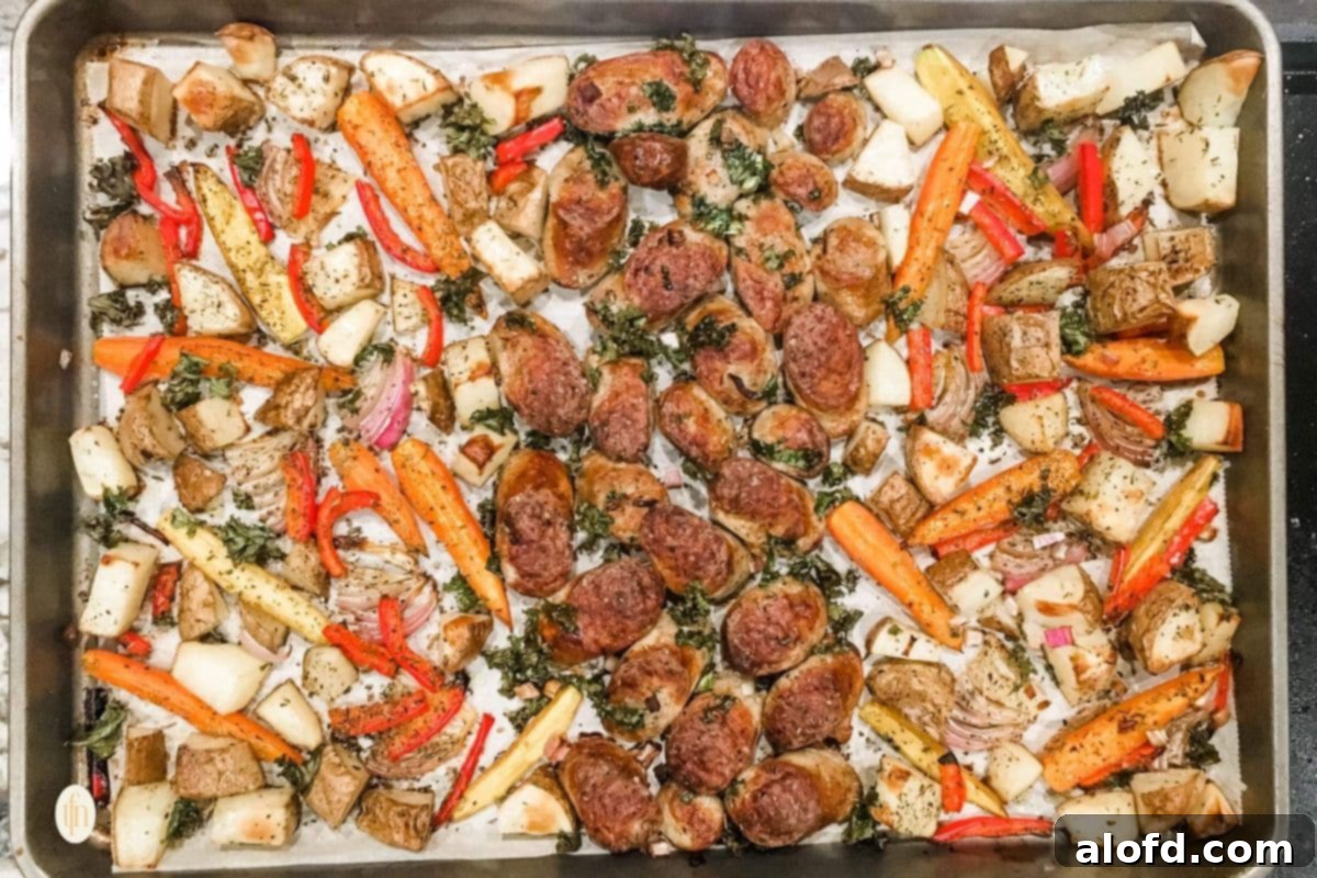 One-Pan Chicken Sausage and Roasted Vegetables 7 A wide, appetizing shot of a sheet pan filled with golden-brown chicken sausage and a rich variety of mixed, roasted vegetables.