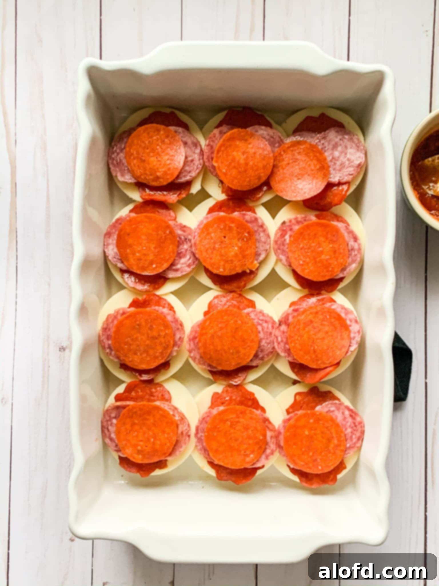 Zesty Italian Slider Bites 9 Assembling mini sandwiches with salami, pepperoni, and cheese.