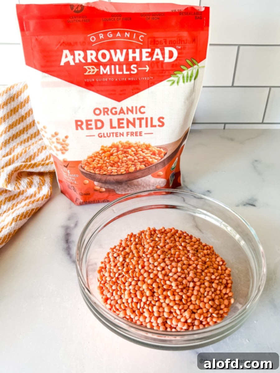 An unopened package of Arrowhead Mills organic red lentils, showcasing their natural, unpolished state and vibrant orange hue.
