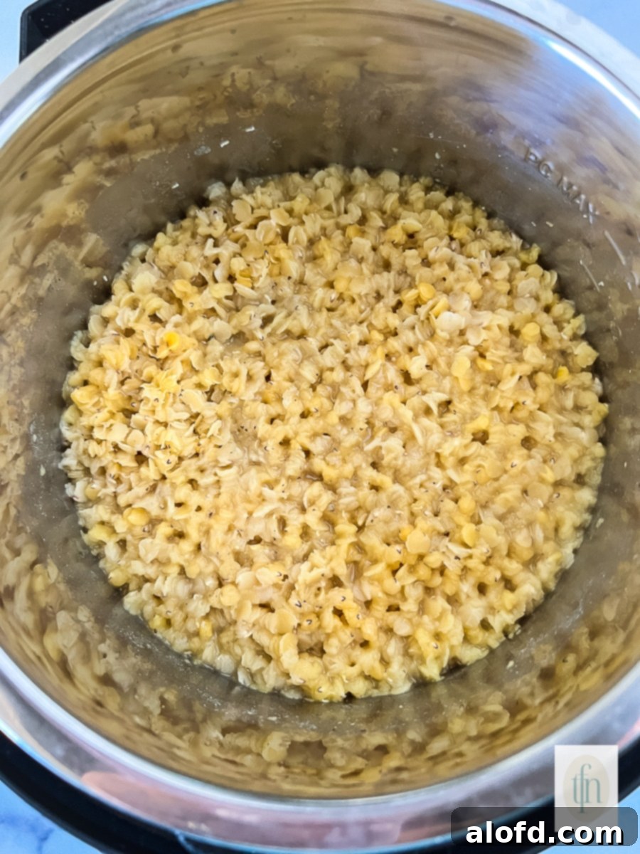 Close-up shot of vibrant red lentils actively cooking and simmering inside an Instant Pot, with gentle steam escaping, showcasing the efficient pressure cooking process.