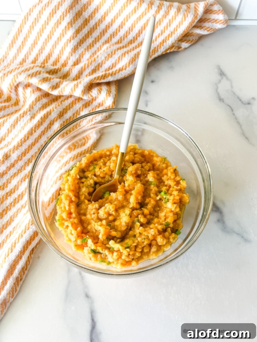 A beautifully presented serving dish of cooked red lentils, garnished with fresh vibrant herbs, ready to be enjoyed as a wholesome meal.